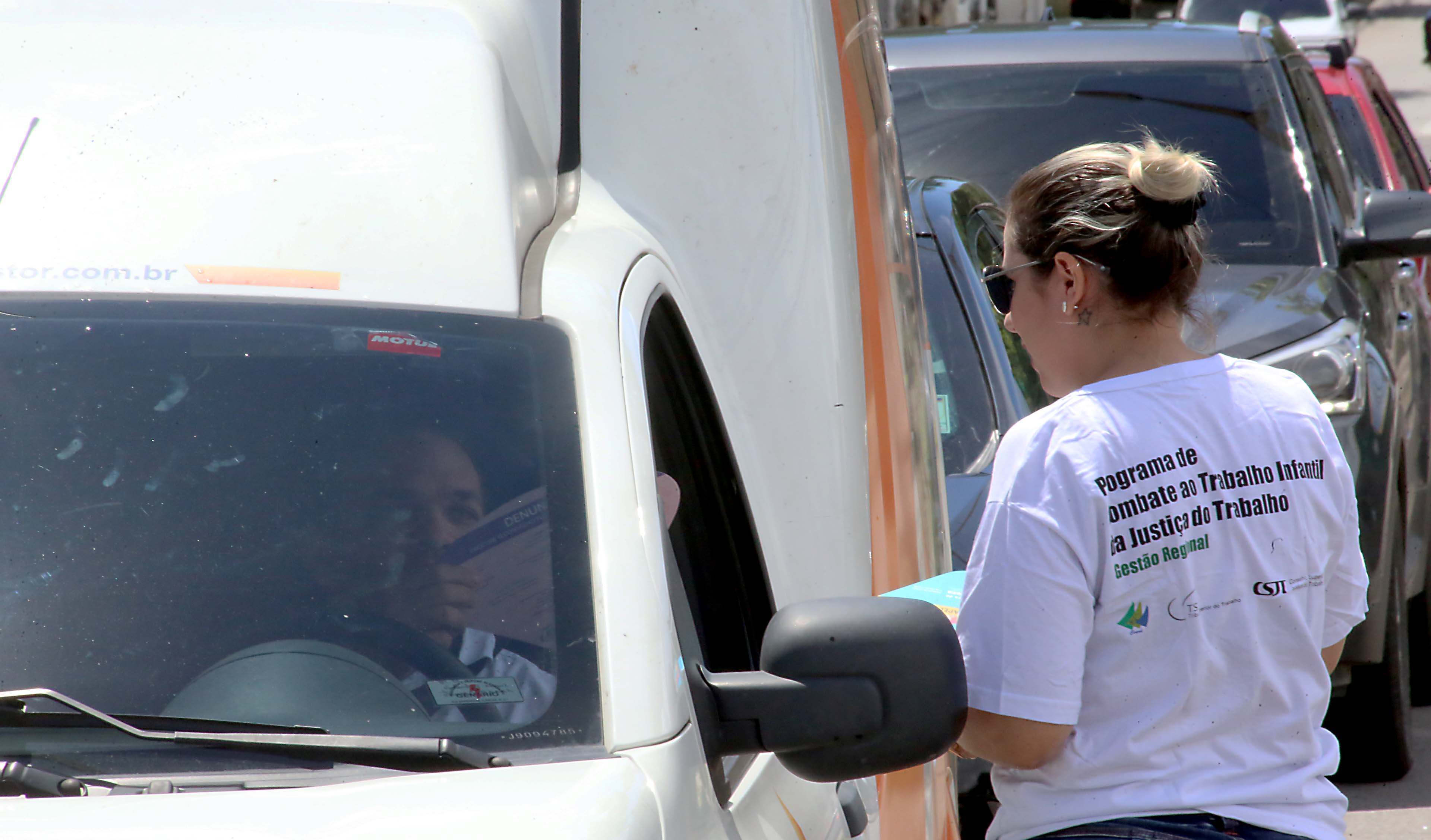 muher entrega panfleto a um motorista de carro